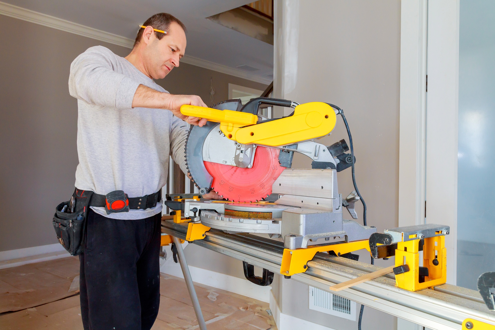 Experienced carpenter cuts wooden molding trim with an electric circular saw at a sawmill